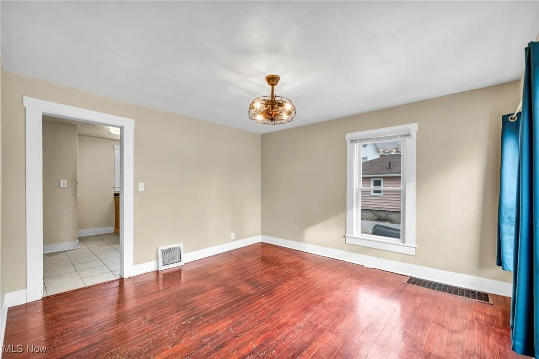 Unfurnished room with hardwood / wood-style floors and a chandelier