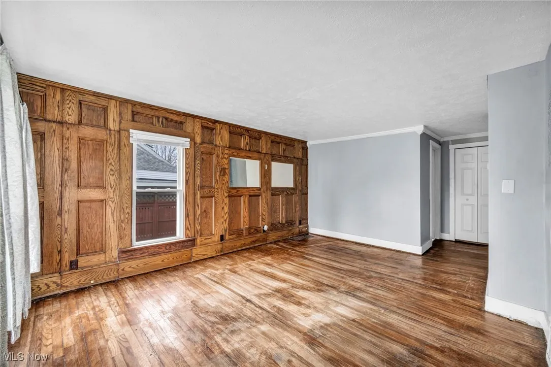 Spare room with hardwood / wood-style flooring, ornamental molding, and a textured ceiling
