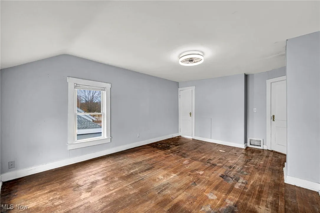 Unfurnished bedroom with dark wood-style floors and lofted ceiling