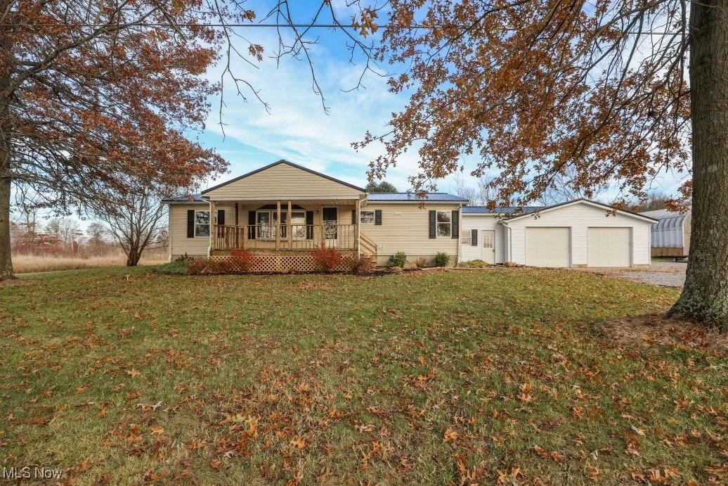 View of front facade featuring a front lawn, an outdoor structure, a garage, and driveway
