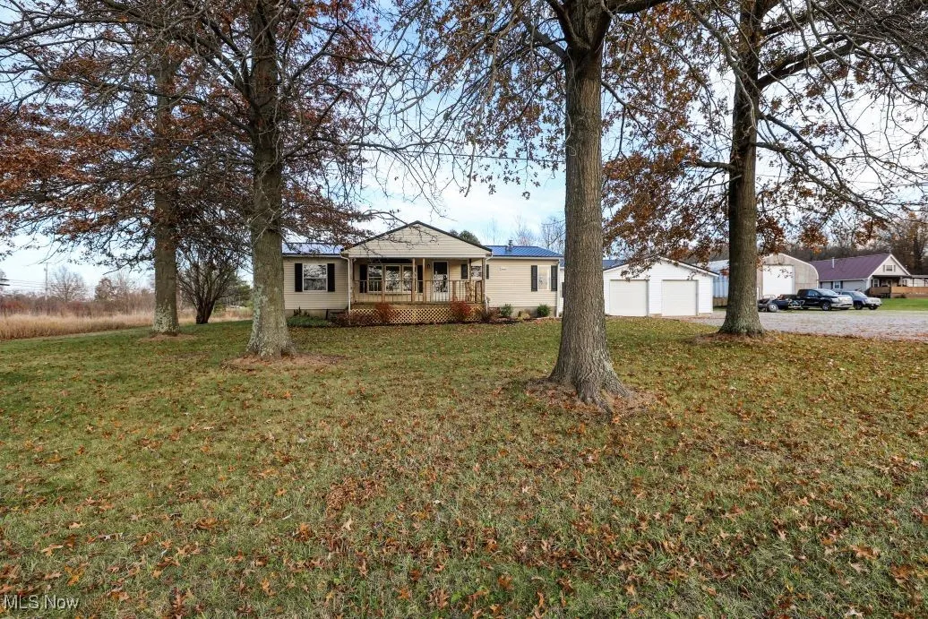 Bungalow featuring a garage, a front yard, an outbuilding, and a deck
