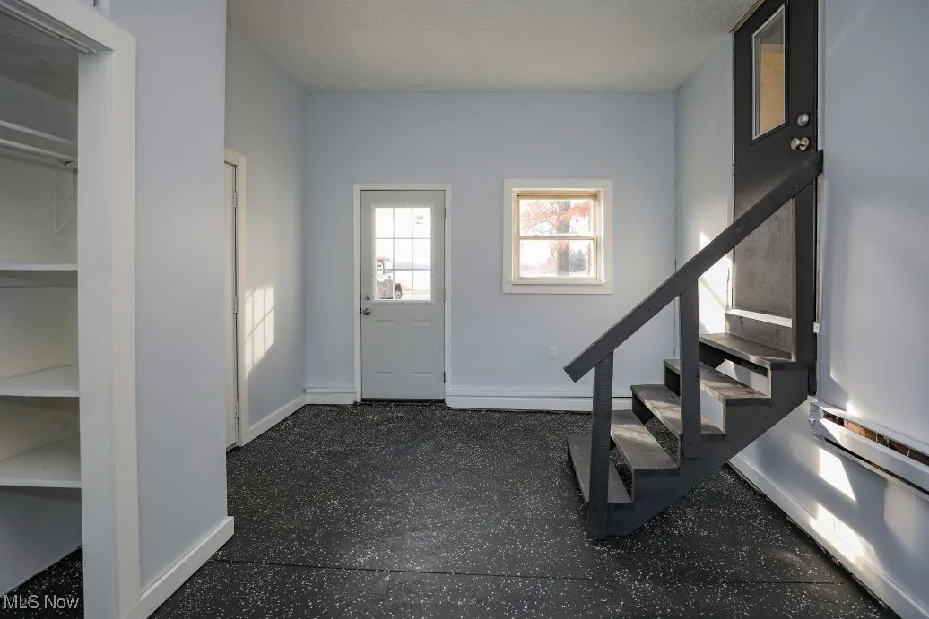 Foyer with stairs, light speckled floor, and a textured ceiling