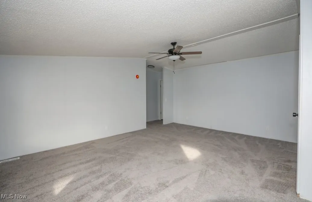 Carpeted spare room with a textured ceiling and a ceiling fan