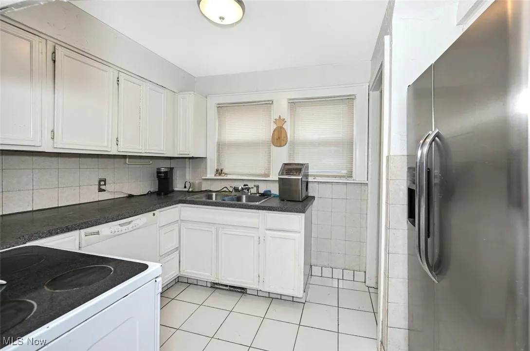 *KITCHEN W/WHITE TILE FLOORING, TILE BACKSPLASH, WHITE CABINETS AND FULLY APPLIANCED INCLUDING A DISHWASHER FOR THE NEW OWNER ~