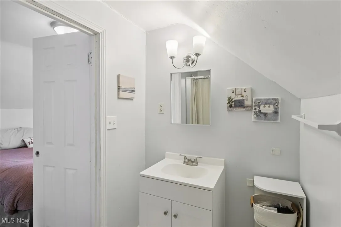 Bathroom featuring vaulted ceiling, vanity, ensuite bath, and a shower with curtain