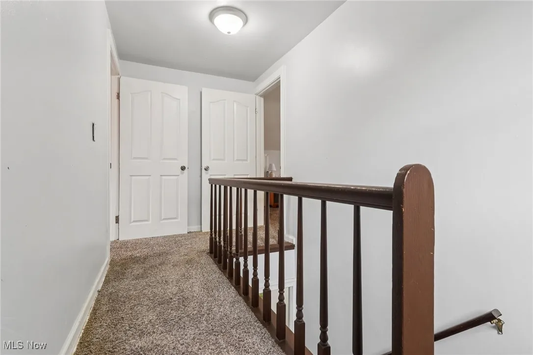 Hallway featuring an upstairs landing and carpet flooring