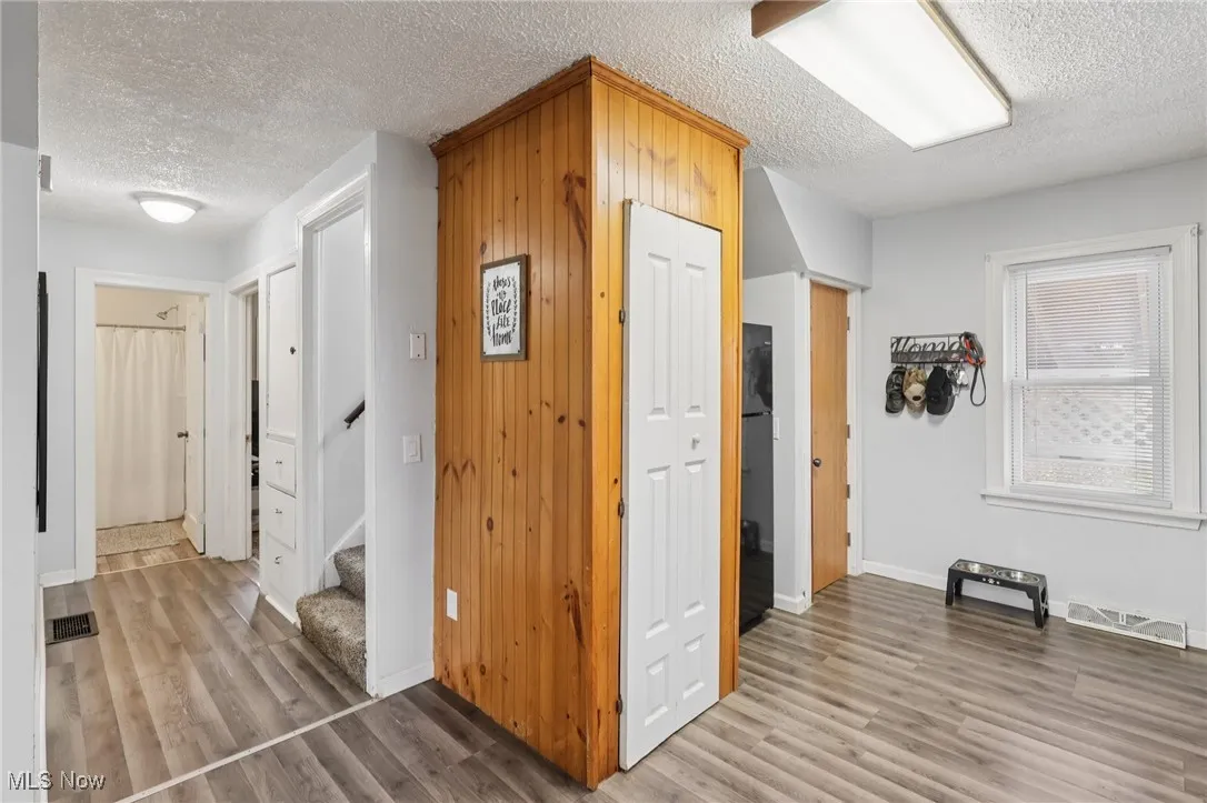 Corridor featuring a textured ceiling, stairway, and light wood-style floors