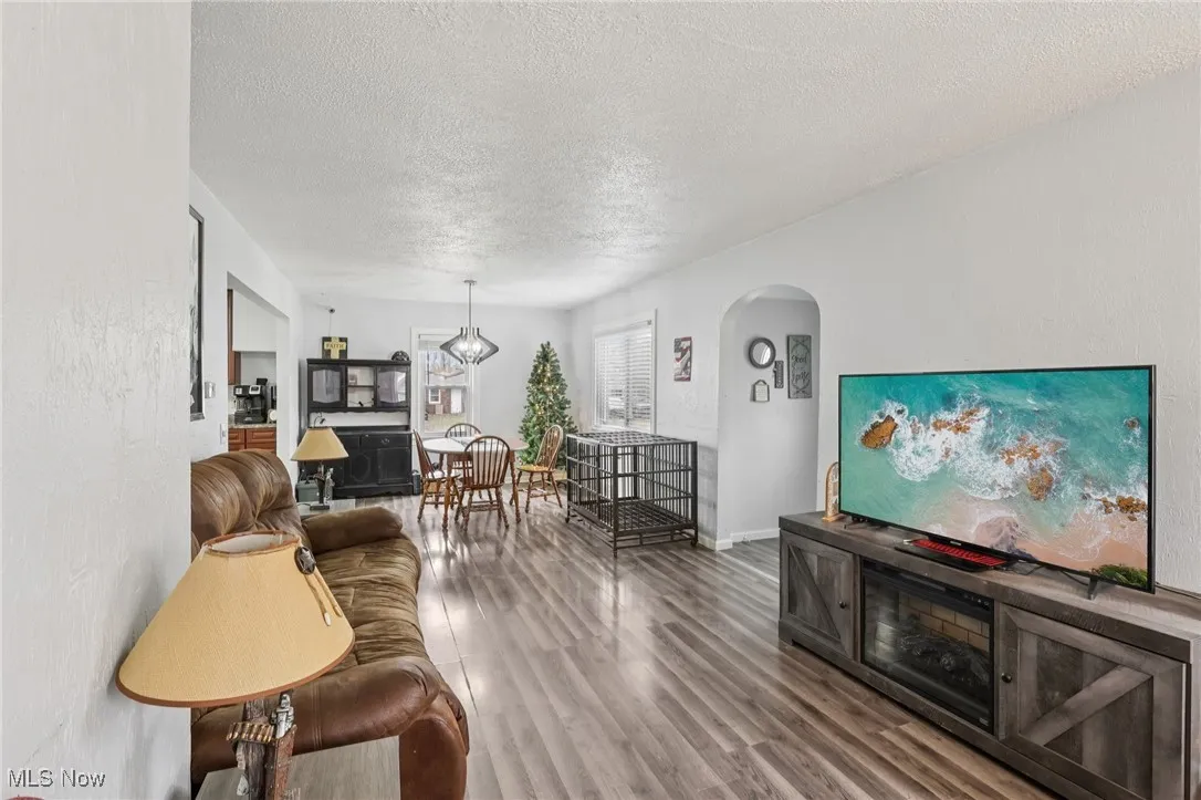 Living room featuring a textured ceiling, wood finished floors, and arched walkways