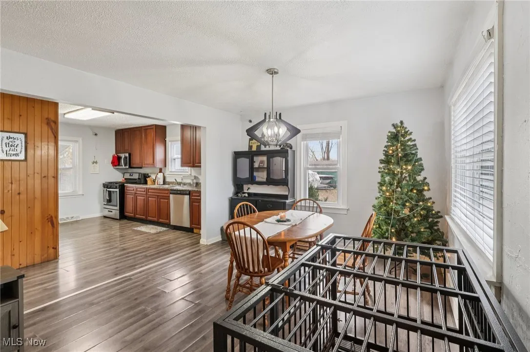 Dining area with a textured ceiling, dark wood-style flooring, and a chandelier