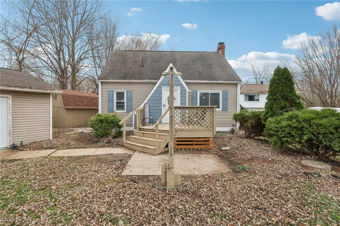 Front of house featuring a deck, a chimney, and roof with shingles
