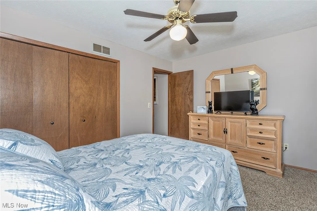 Bedroom with a closet, light colored carpet, and ceiling fan