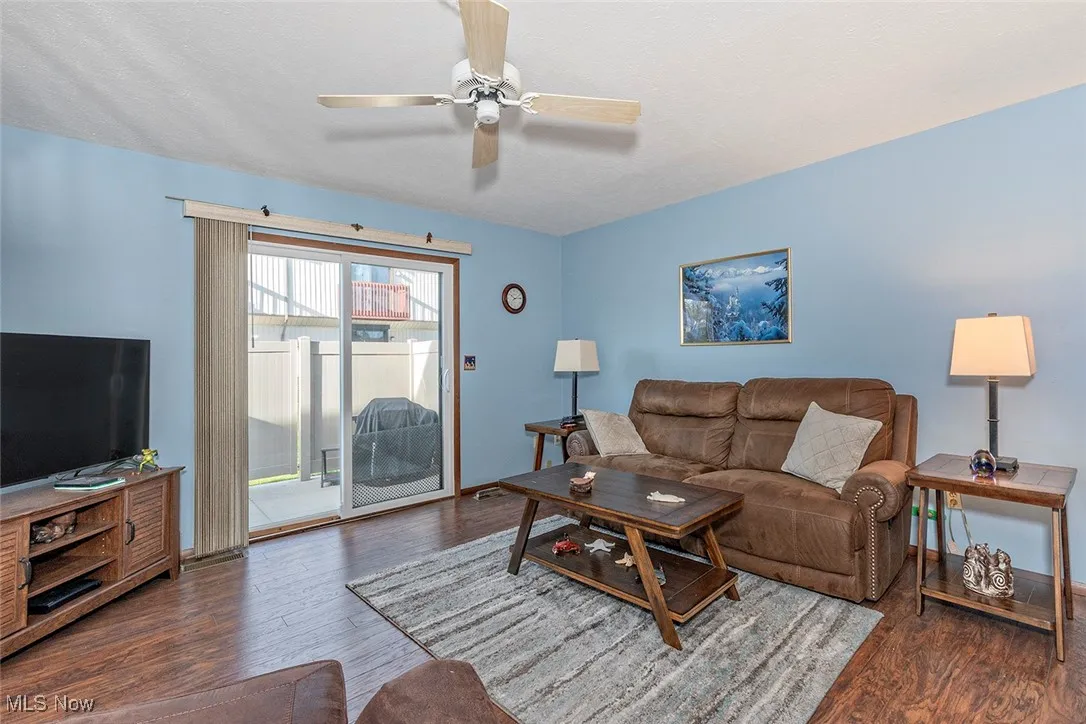 Living area with dark wood-style flooring and a ceiling fan