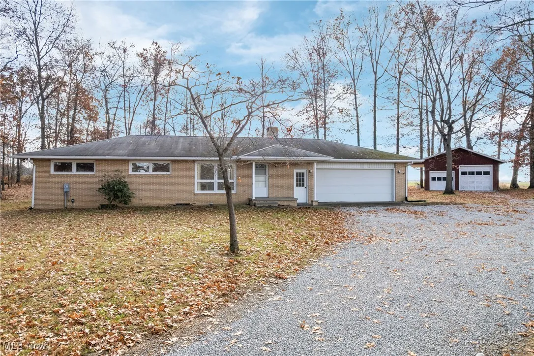 Ranch-style home with brick siding and gravel driveway