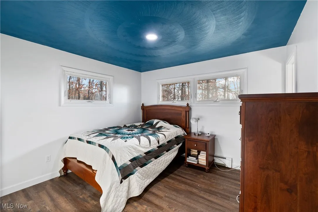 Bedroom featuring dark wood-type flooring and baseboards