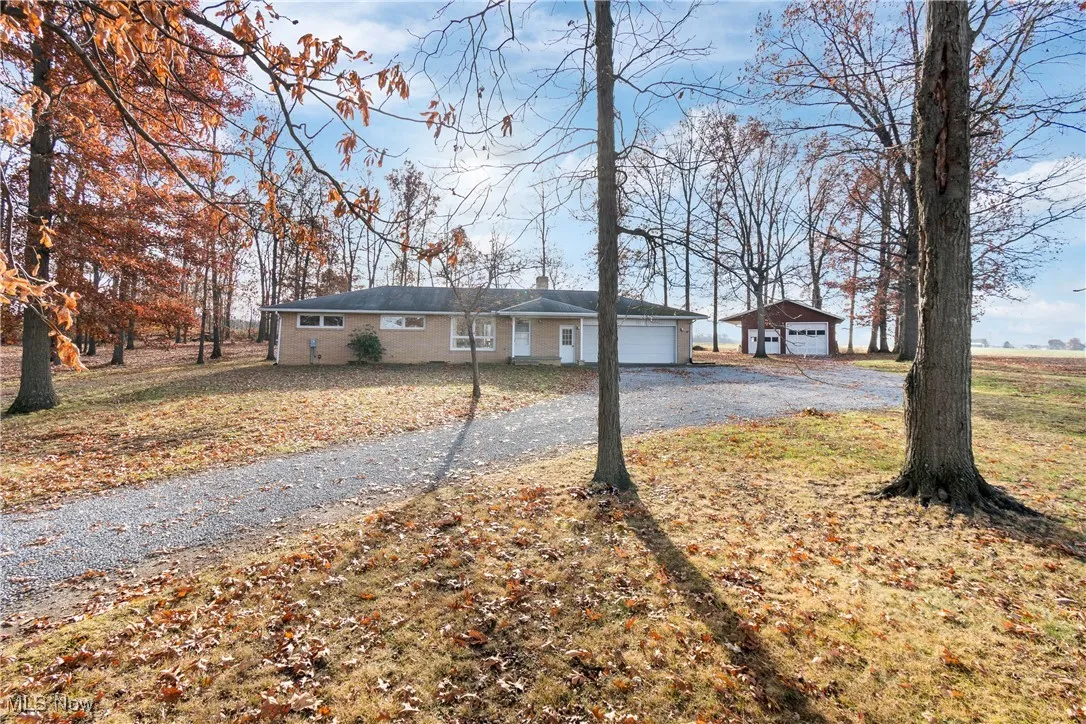 Ranch-style home with a front lawn, driveway, a detached garage, and an outdoor structure