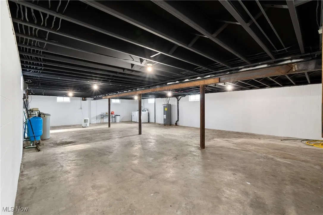 Below grade area featuring water heater, a water pressure tank, washer / dryer, and plenty of natural light