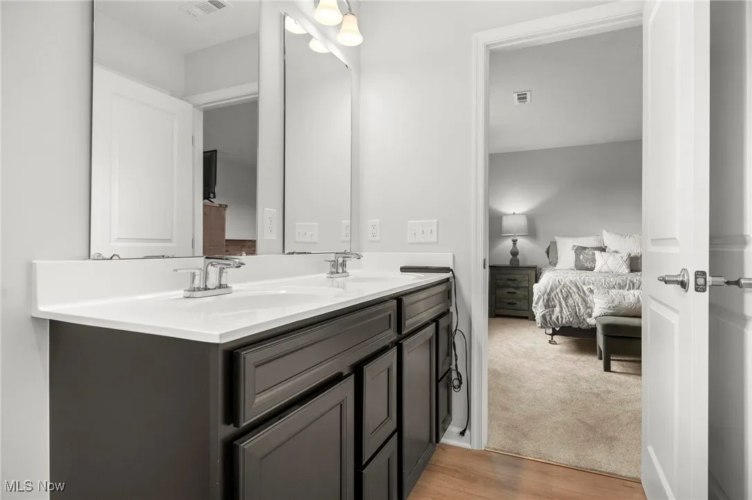 Full bathroom with double vanity, ensuite bathroom, and light colored carpet