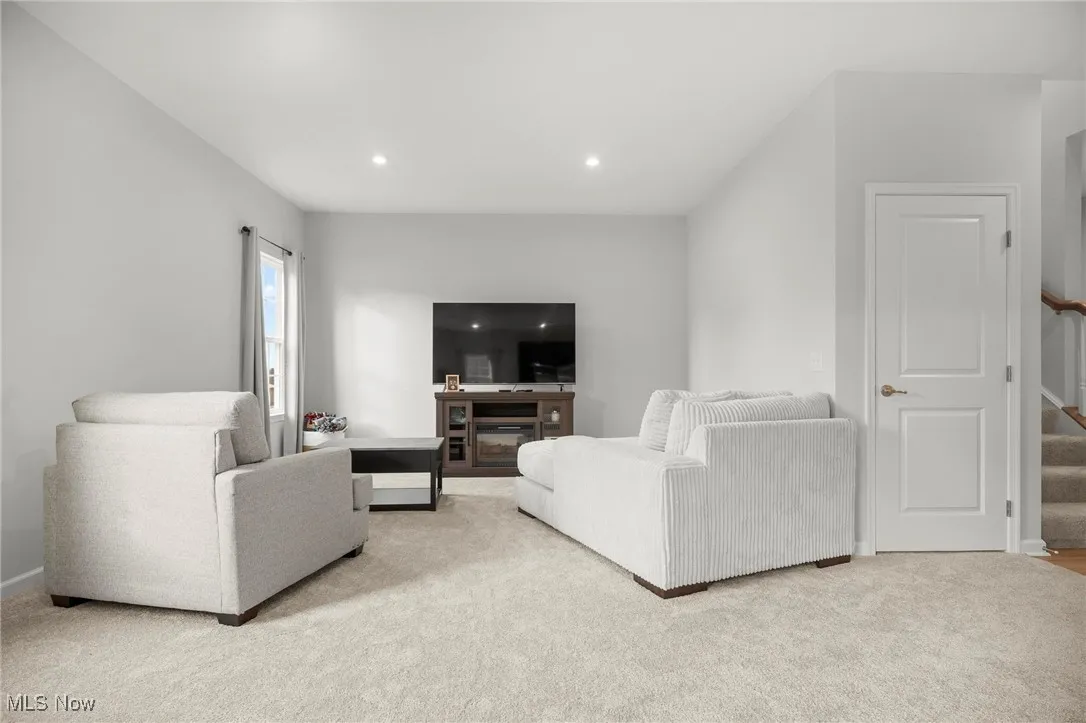 Living area featuring stairs, carpet, a fireplace, and recessed lighting