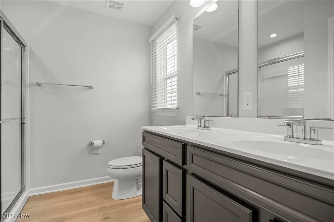Bathroom featuring a shower stall, light wood-style flooring, and double vanity