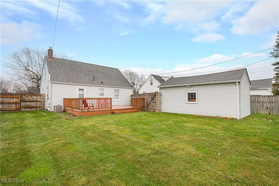 Back of house featuring a fenced backyard, a deck, a shingled roof, and a chimney