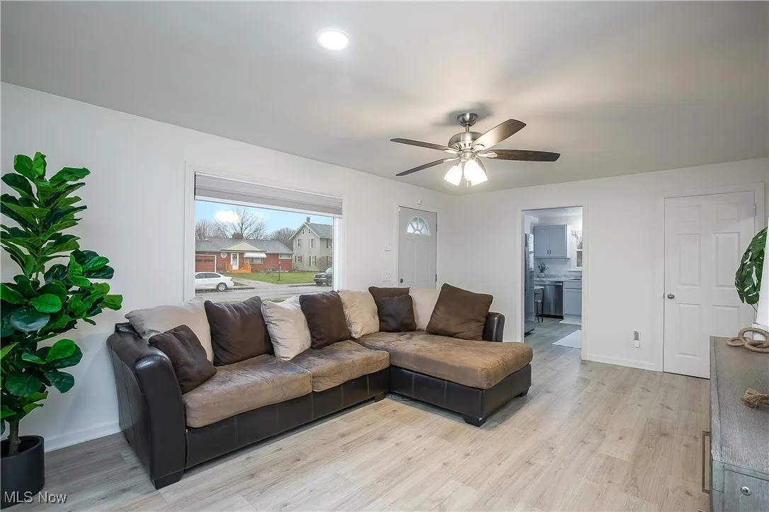 Living room with light wood-style flooring and a ceiling fan