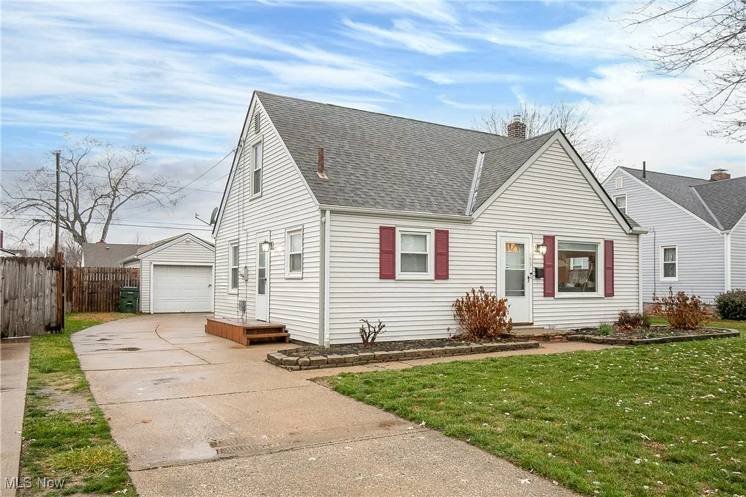 View of front of home with roof with shingles, a chimney, an outdoor structure, a garage, and concrete driveway