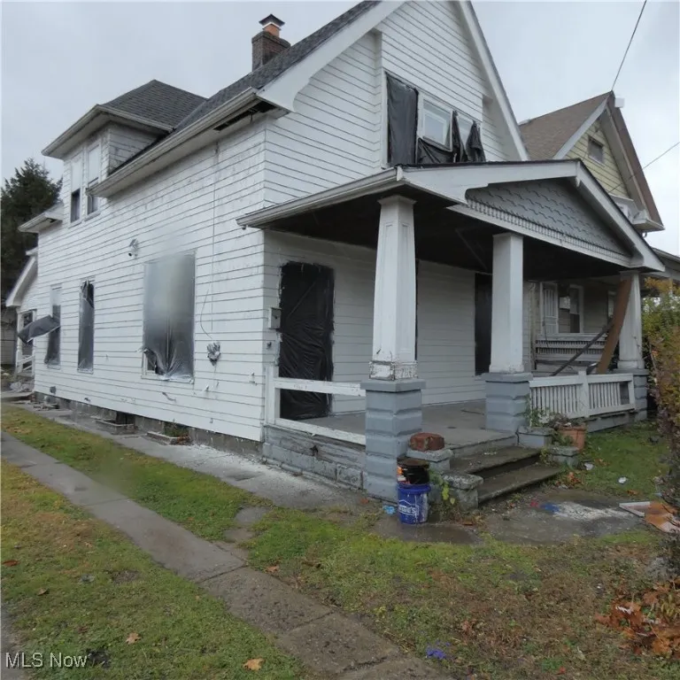 View of side of home featuring covered porch and a chimney