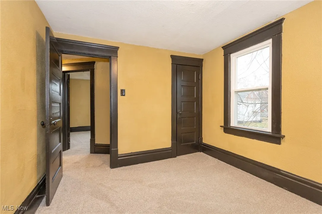 Empty room featuring light colored carpet and a textured ceiling