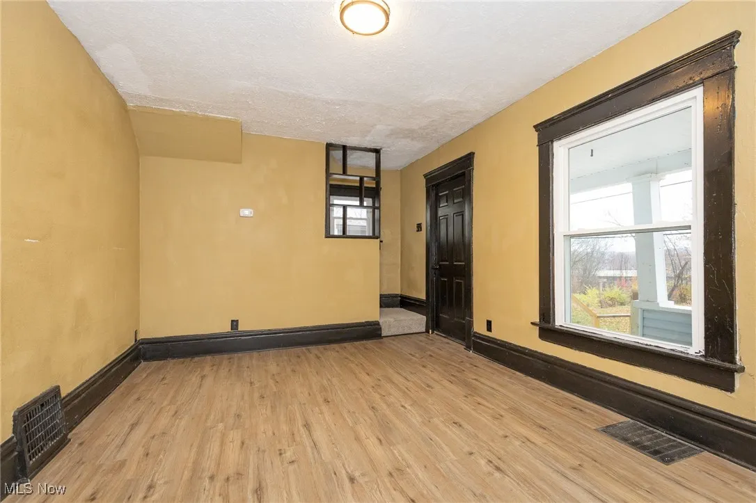 Empty room with a textured ceiling and light wood-type flooring