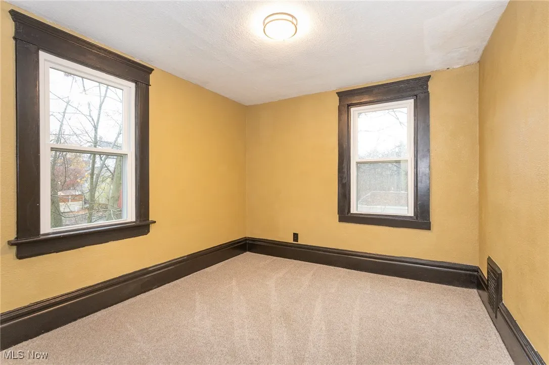 Carpeted empty room with a textured ceiling and baseboards