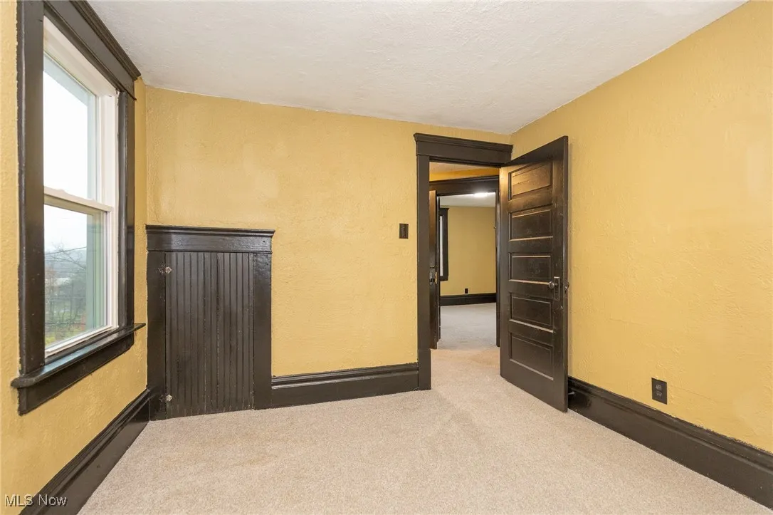Unfurnished room with a textured wall, carpet flooring, and a textured ceiling