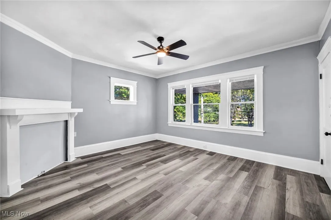 Unfurnished living room with ornamental molding, light wood-type flooring, a ceiling fan, and a fireplace