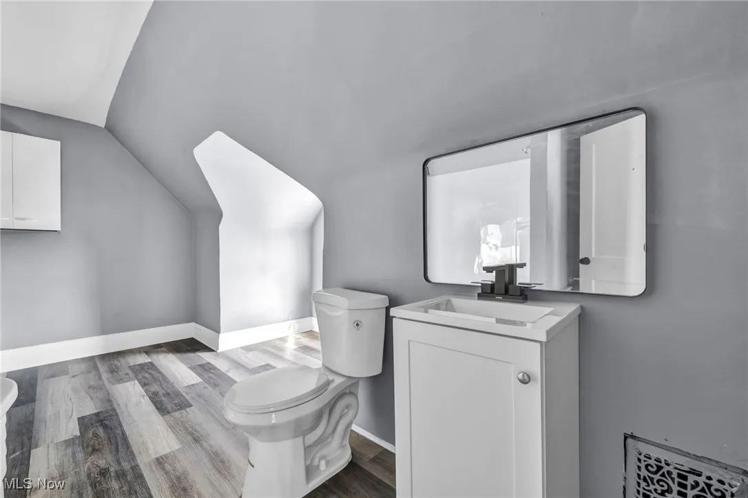 Bathroom with vanity, dark wood-style floors, and lofted ceiling