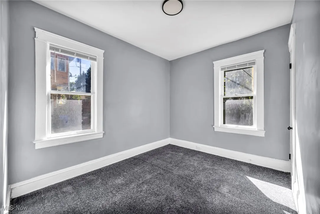 Empty room featuring dark colored carpet and baseboards