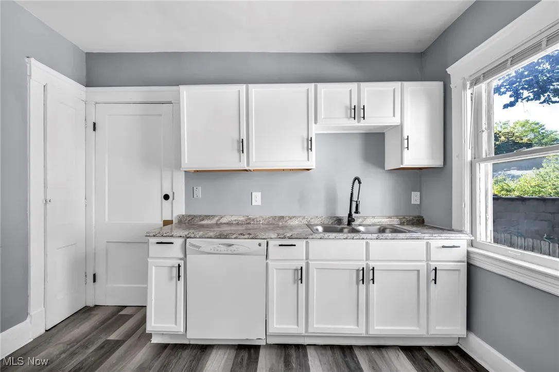 Kitchen with white cabinetry, dishwasher, light countertops, and dark wood-type flooring