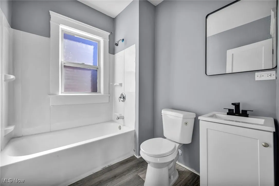 Full bathroom with shower / tub combination, vanity, and dark wood-style floors