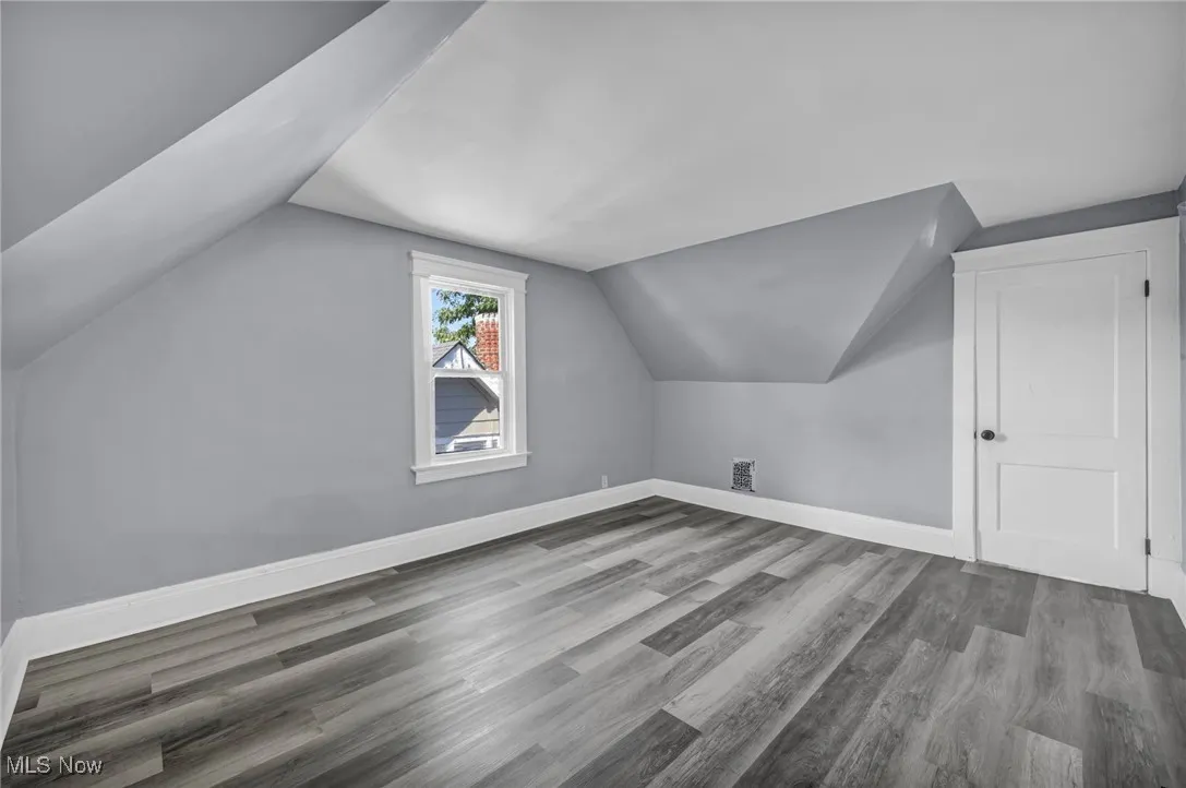 Bonus room with light wood-style flooring and lofted ceiling