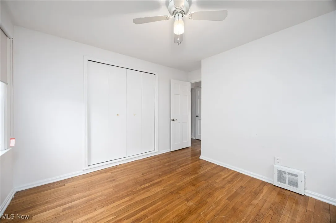 Unfurnished bedroom with wood-type flooring, a ceiling fan, and a closet