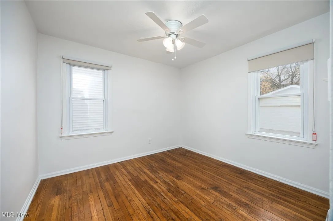 Unfurnished room with dark wood-style floors and a ceiling fan