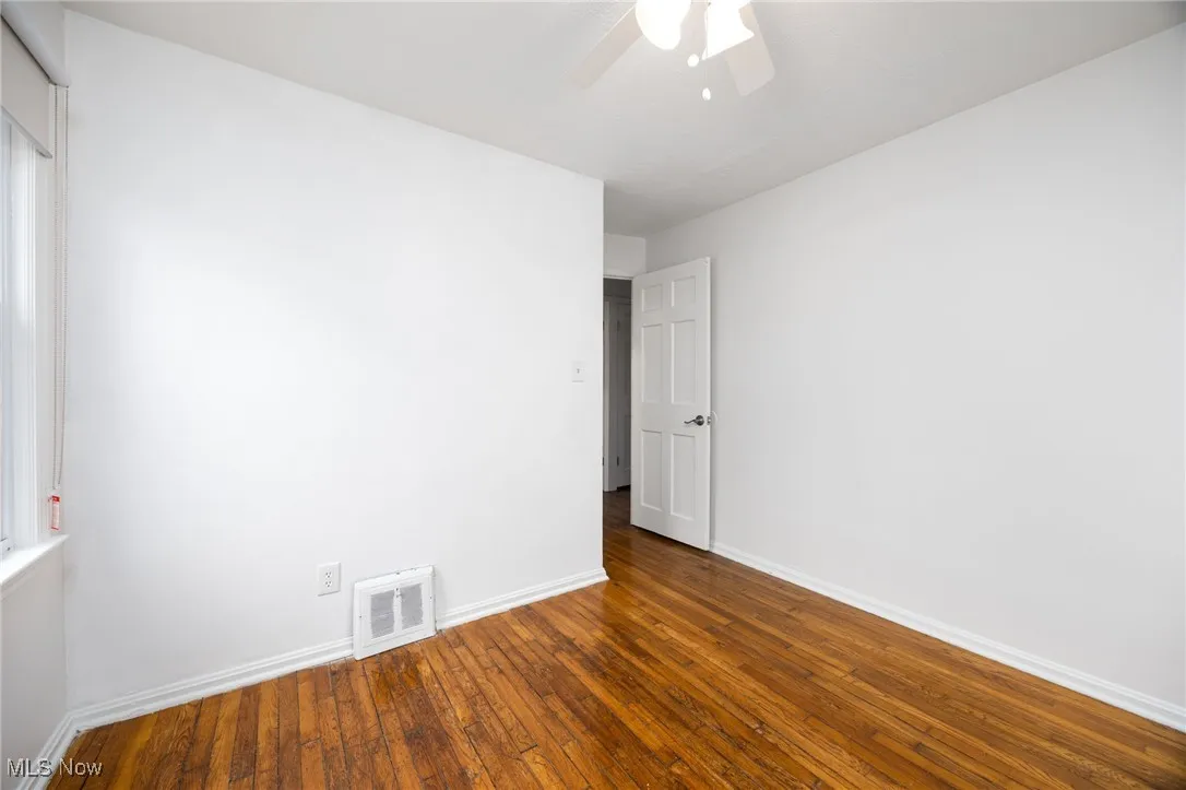 Empty room with hardwood / wood-style floors and a ceiling fan