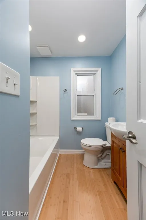 Bathroom featuring vanity, light wood-type flooring, tub / shower combination, and recessed lighting