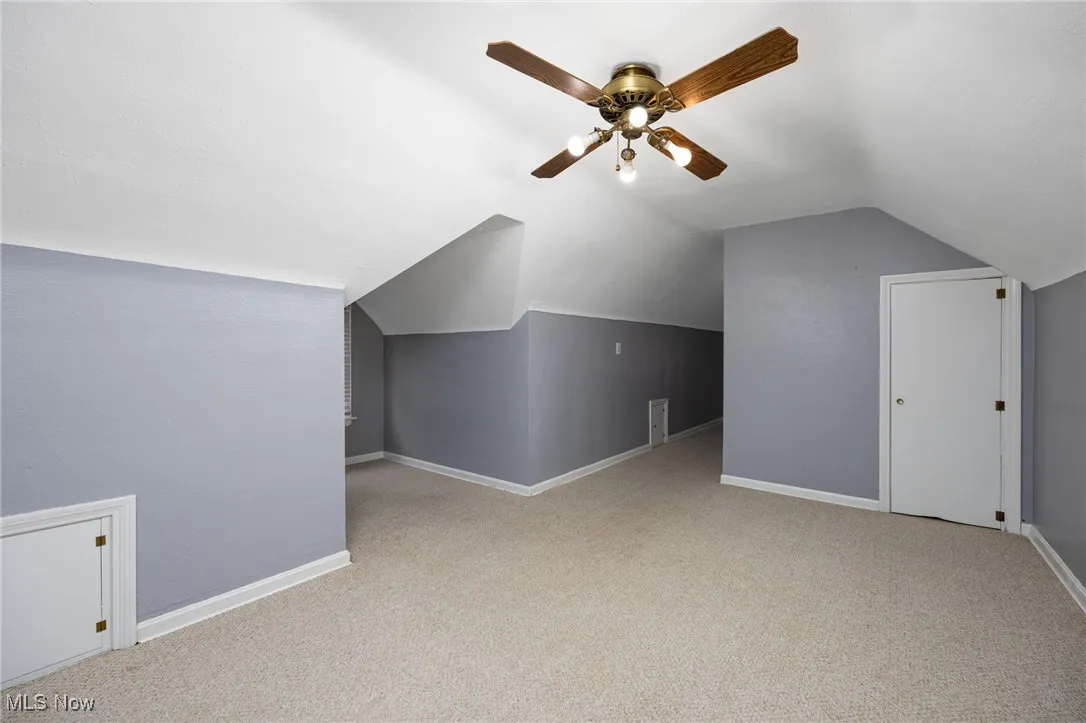 Bonus room with lofted ceiling, light carpet, and a ceiling fan
