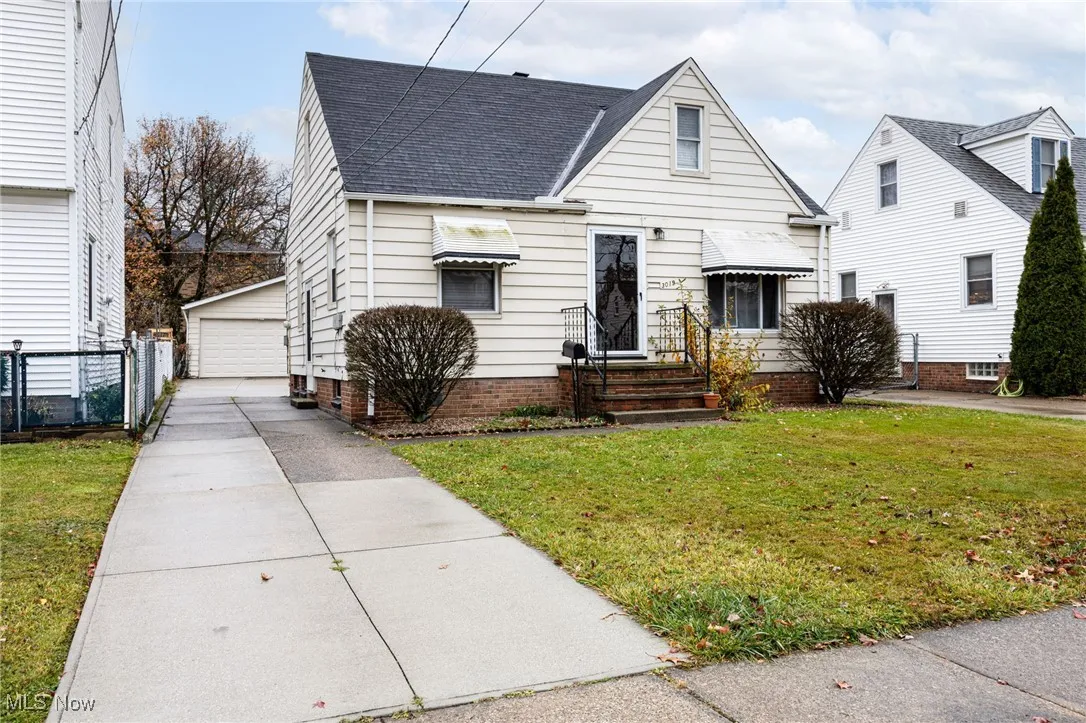 View of front of home with a shingled roof, an outbuilding, and a garage