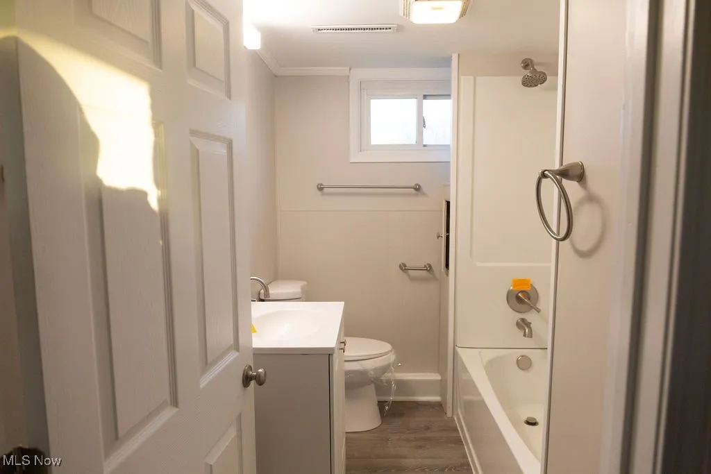 Bathroom with vanity, washtub / shower combination, dark wood finished floors, and crown molding