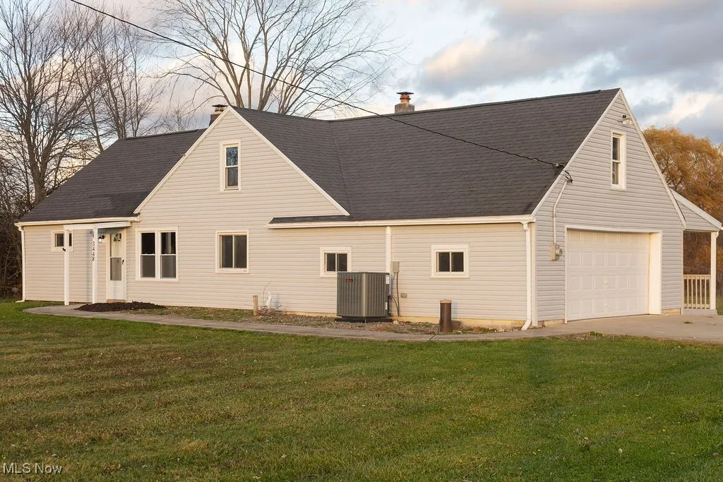 View of front of the property featuring a yard, a chimney, a garage, a shingled roof, and driveway