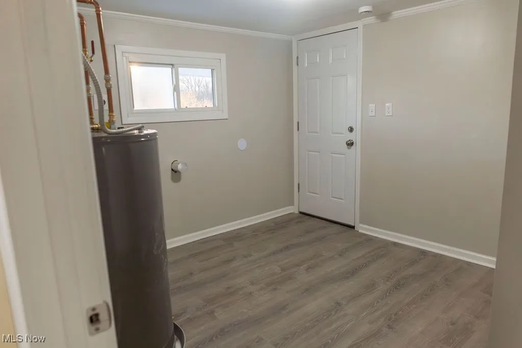Laundry area featuring water heater, wood finished floors, and ornamental molding