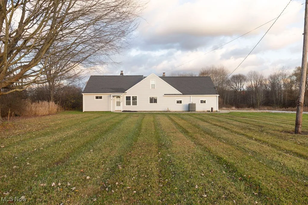 View of front of the property featuring a yard, a chimney, a garage, a shingled roof, and driveway
