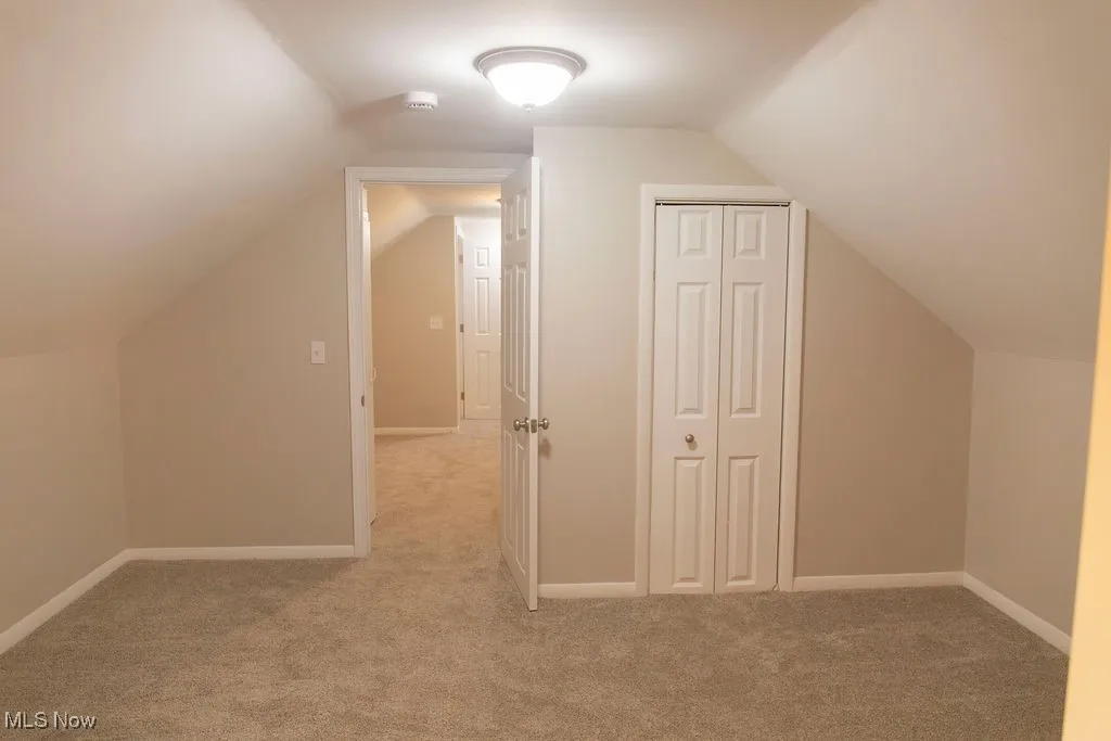 Additional living space with light carpet and lofted ceiling