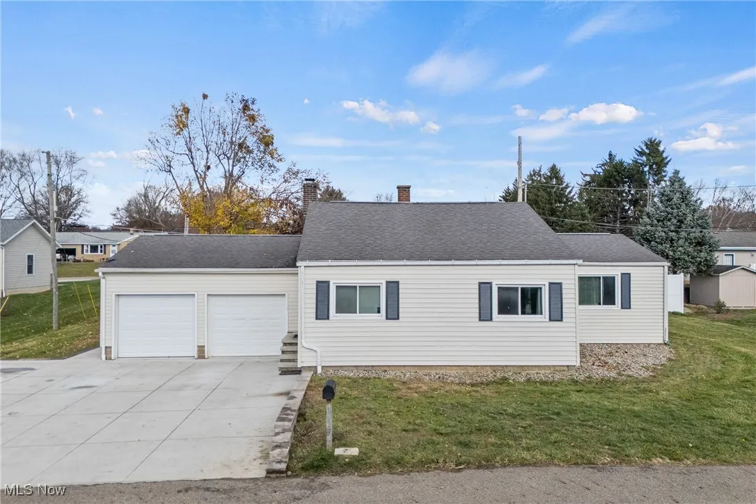 View of front of house with a front yard, driveway, a garage, and a chimney