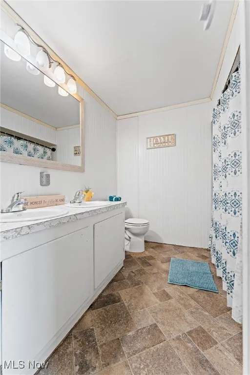 Bathroom featuring stone tile flooring, a shower with shower curtain, and double vanity